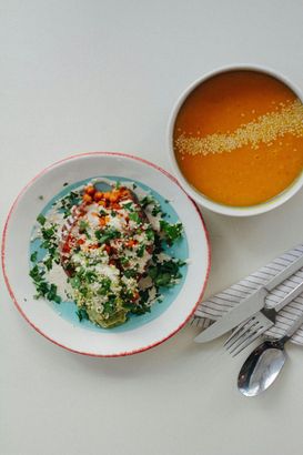 A bowl of soup and a plate of food on a table.