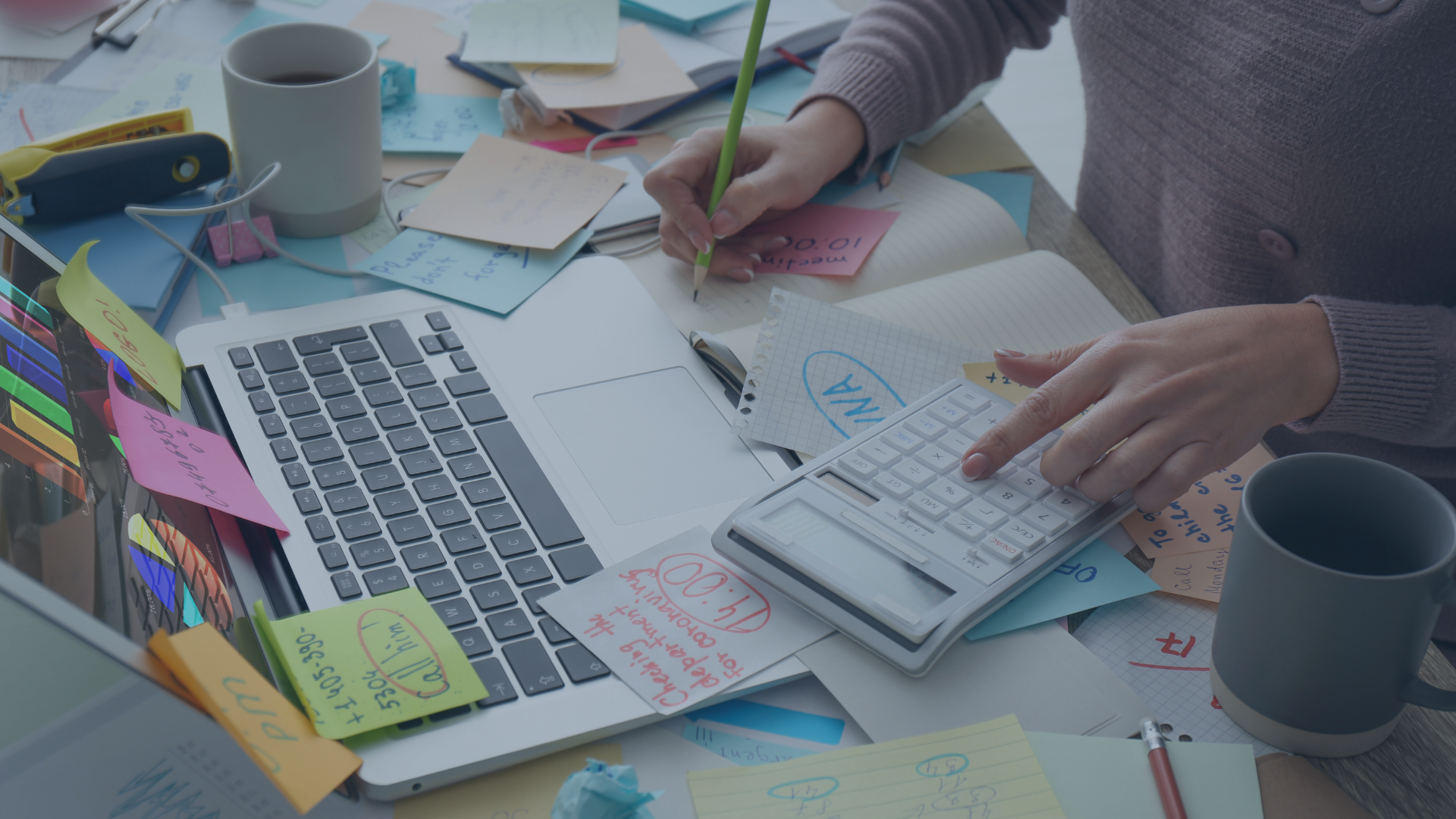 Überfüllter Schreibtisch mit Laptop, Notizzetteln, Taschenrechner und Kaffeetasse – symbolisiert Stress und hohe Arbeitsbelastung im Büroalltag.