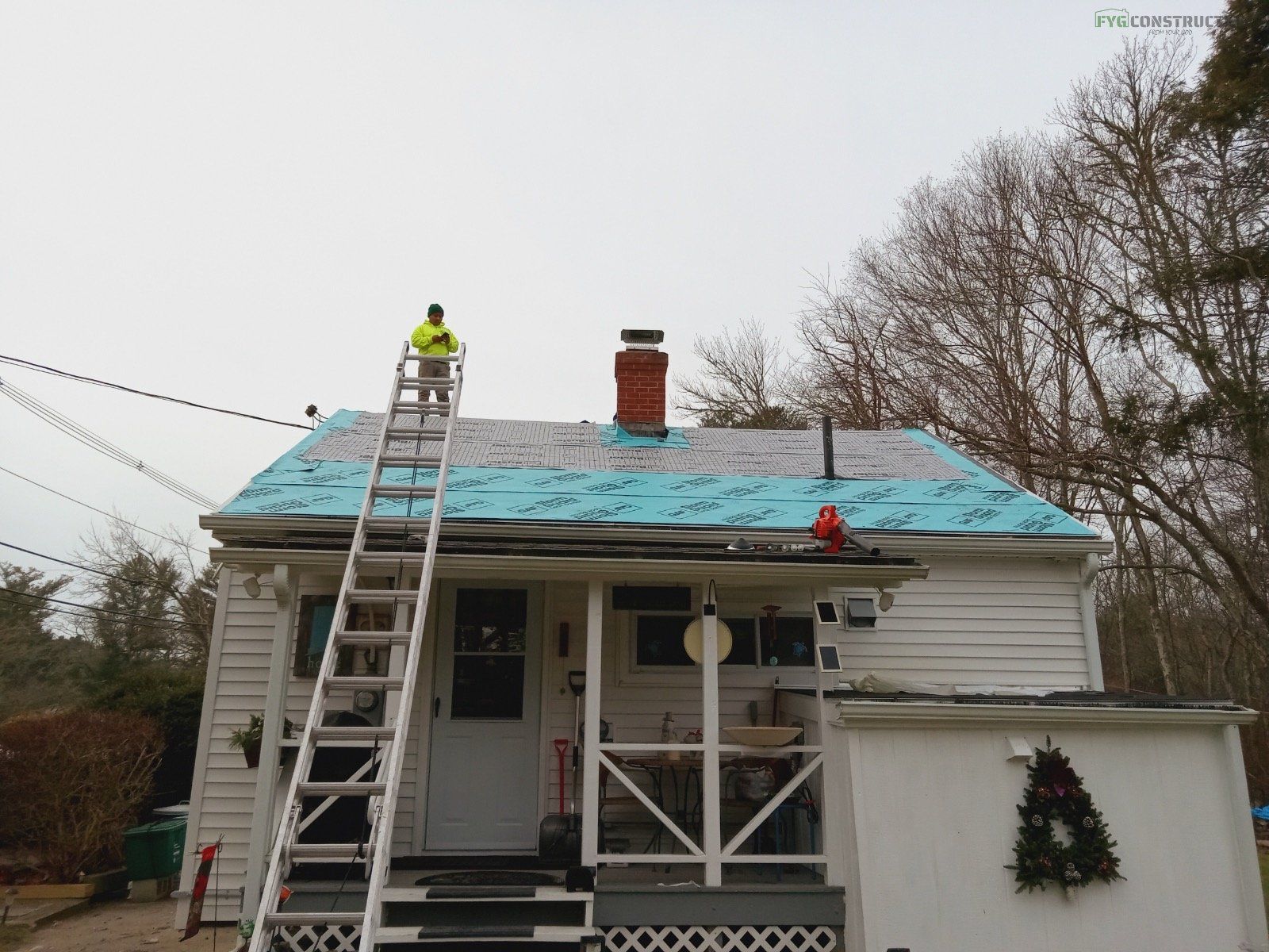 A roofer on a ladder installing a roof