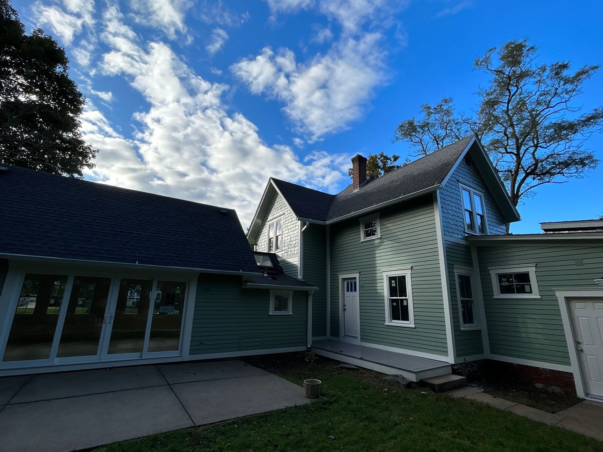 A large green house with a blue roof is sitting on top of a lush green lawn.