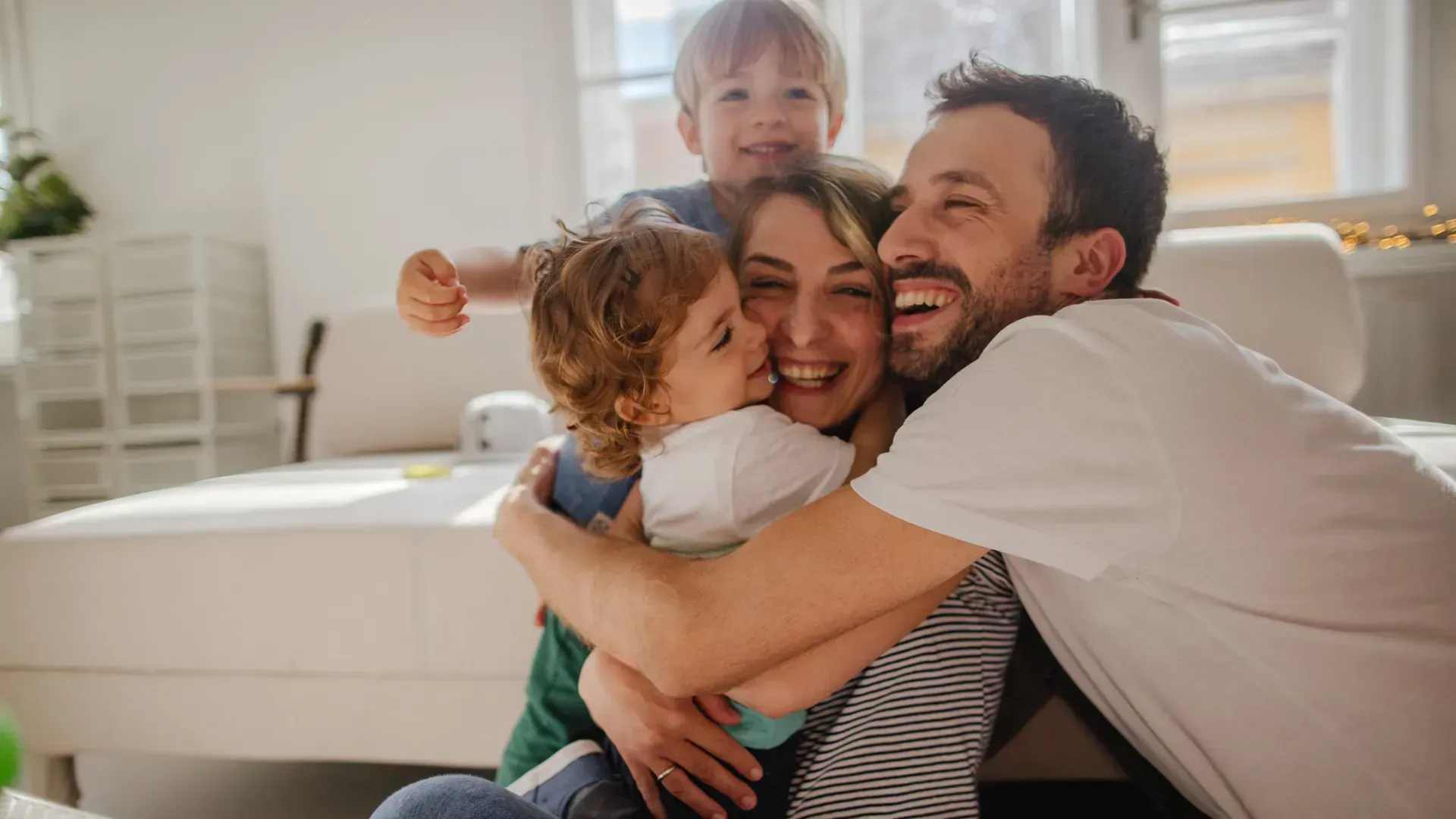 A family is hugging each other on a couch in a living room.