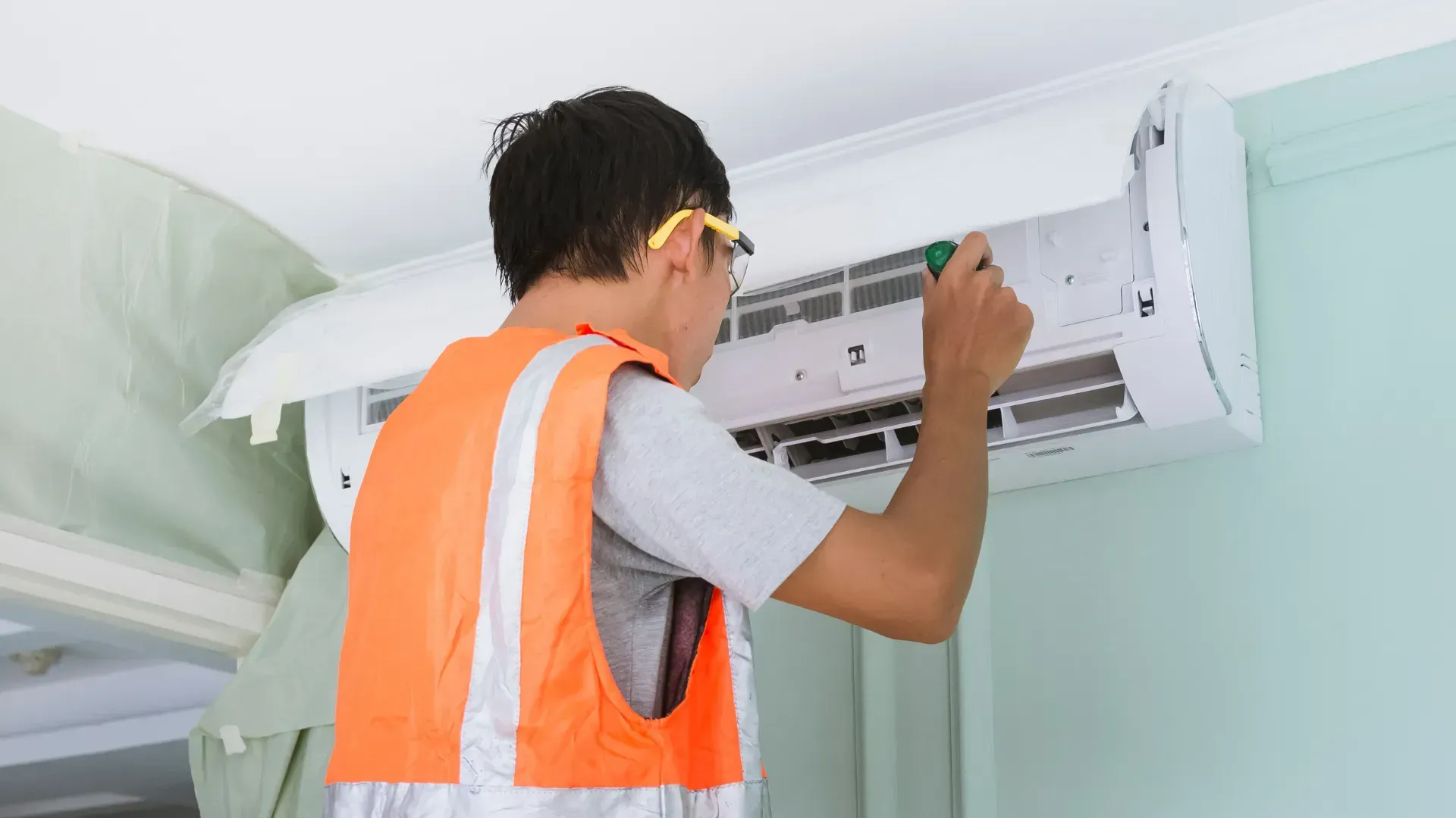 A man is working on an air conditioner in a room.