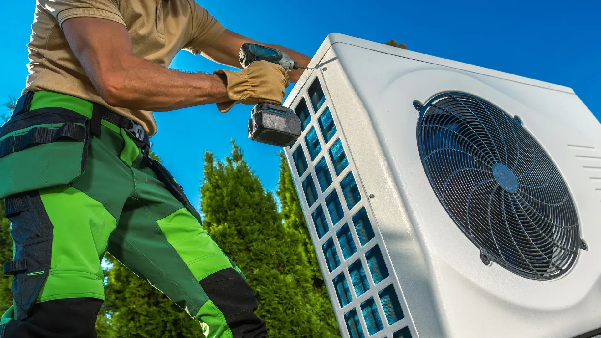 A man is working on an air conditioner with a drill.