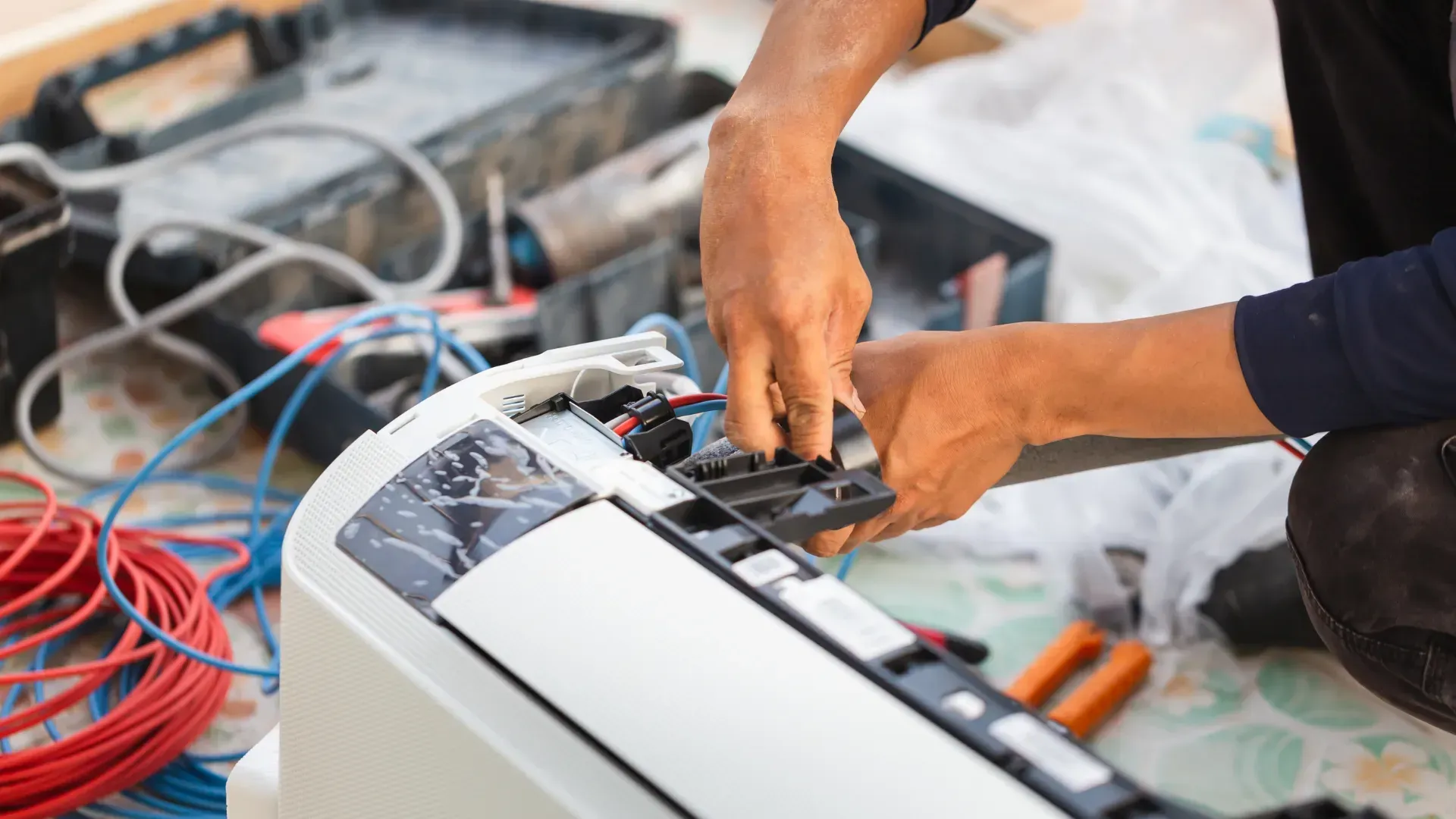 A man is fixing an air conditioner on the floor.