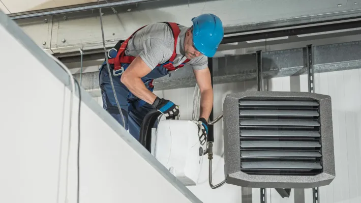 A man is working on a heater in a building.