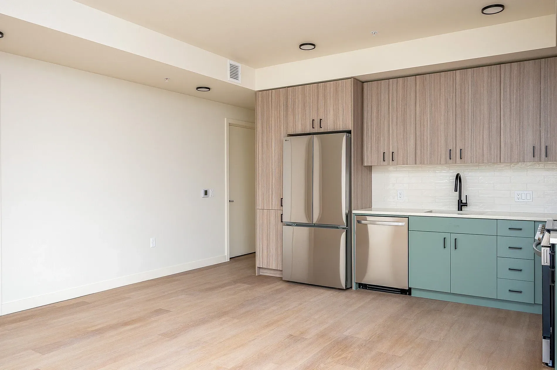 Modern kitchen with stainless steel refrigerator, dishwasher, and cabinetry.
