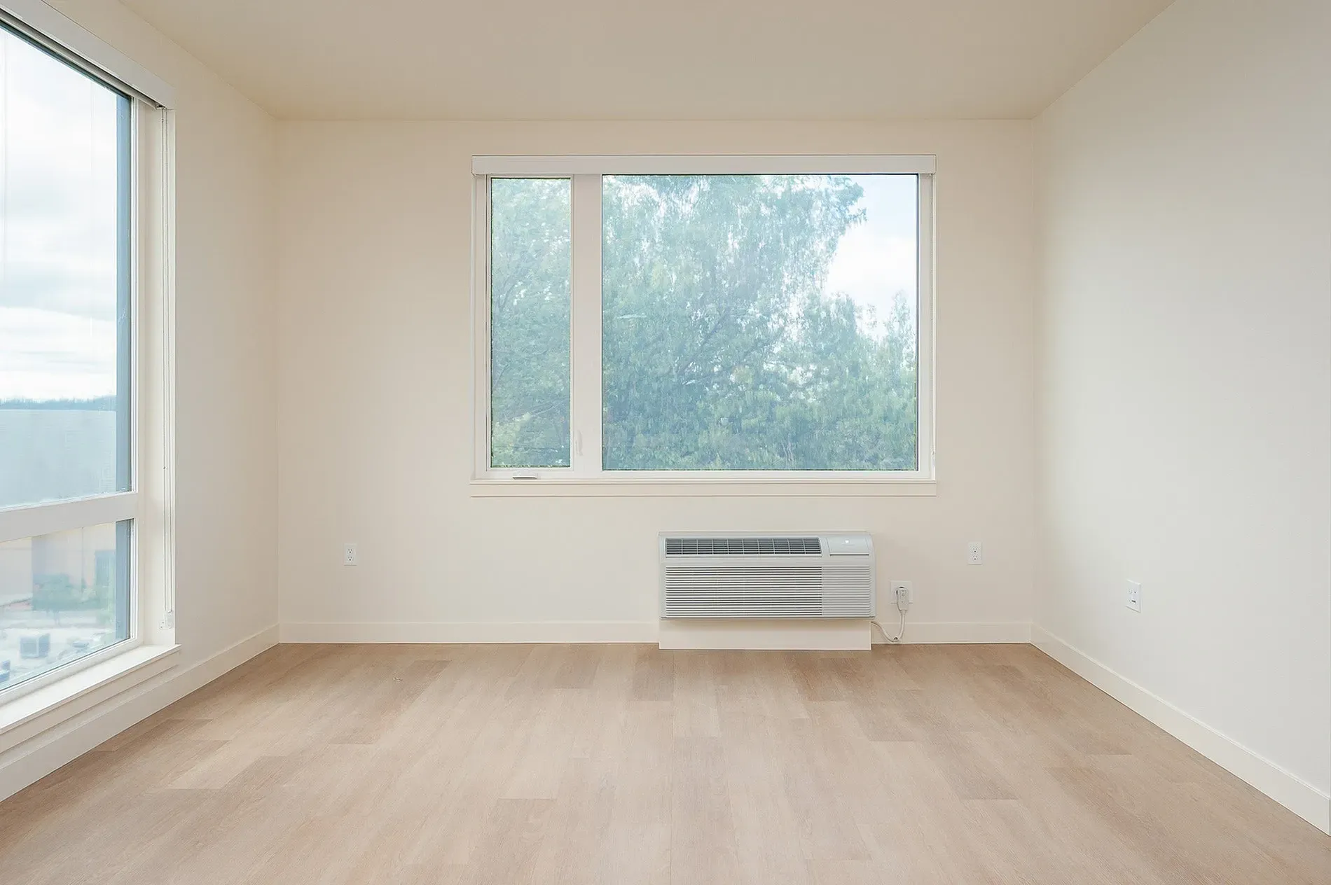Empty living room with large windows and wood flooring