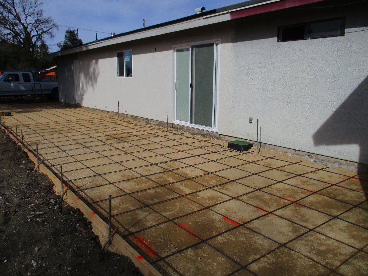 Backyard patio with rebar grid and concrete forms beside a white house