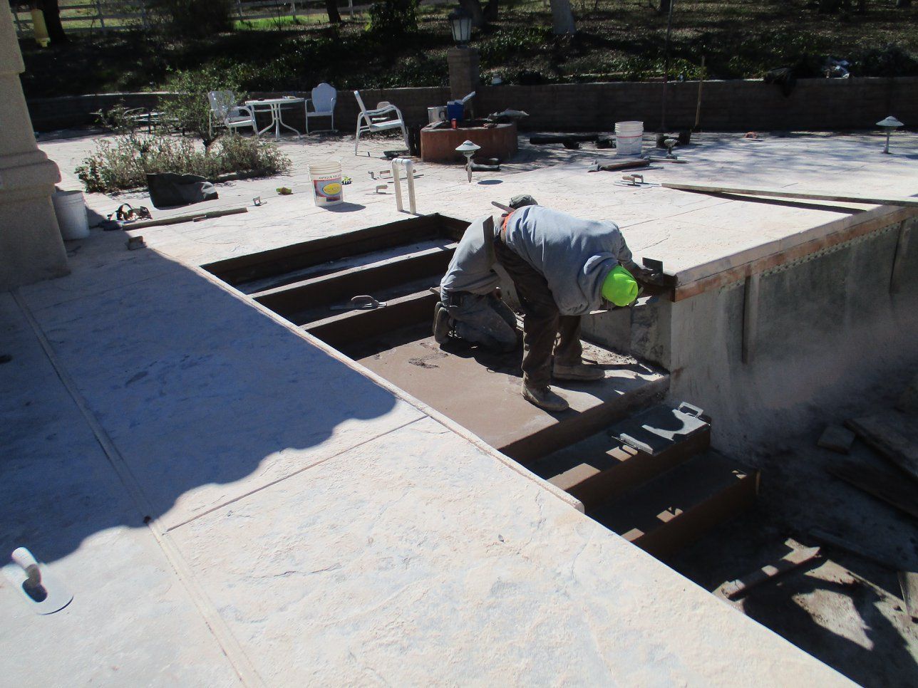 Construction worker in hard hat and safety vest descending stairs on a concrete structure outdoors