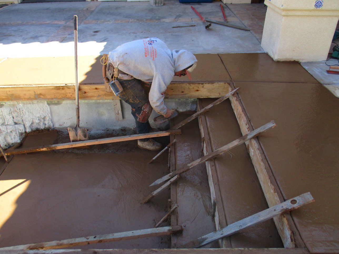 Worker on a concrete form pouring wet cement at a construction site