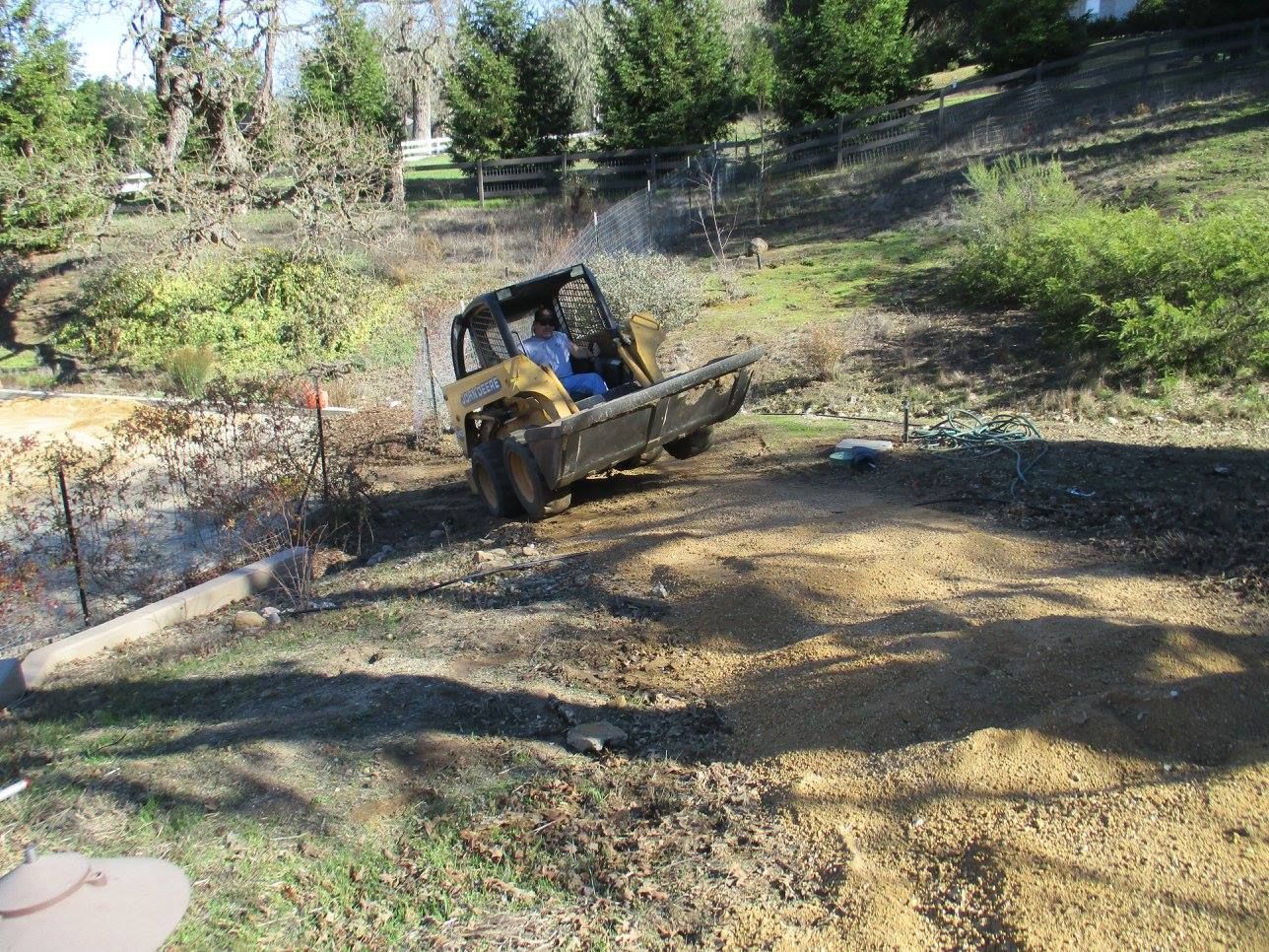 Bulldozer working on a dirt path in a wooded hillside area