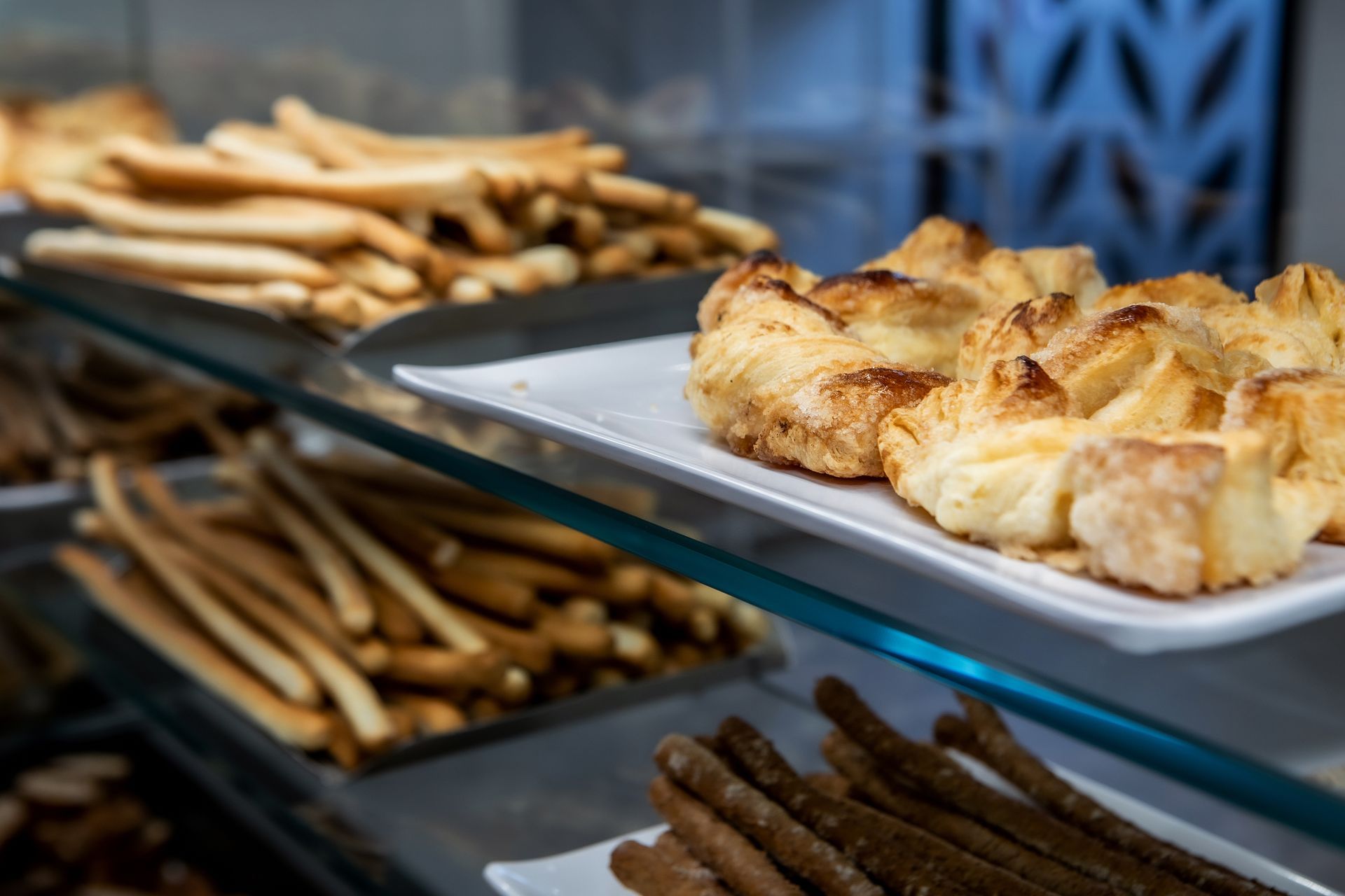 Prodotti da forno esposti in una vetrina, tra cui grissini e pasticcini.