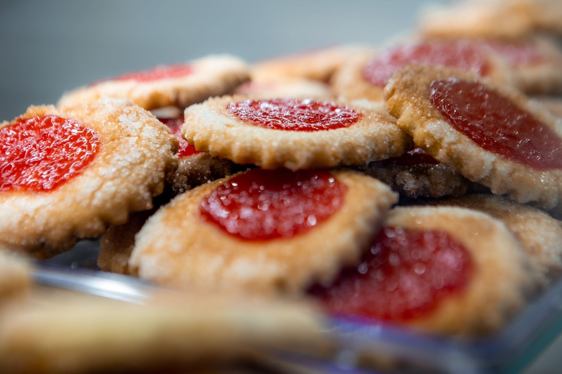 Mucchio di biscotti rotondi con marmellata rossa al centro.