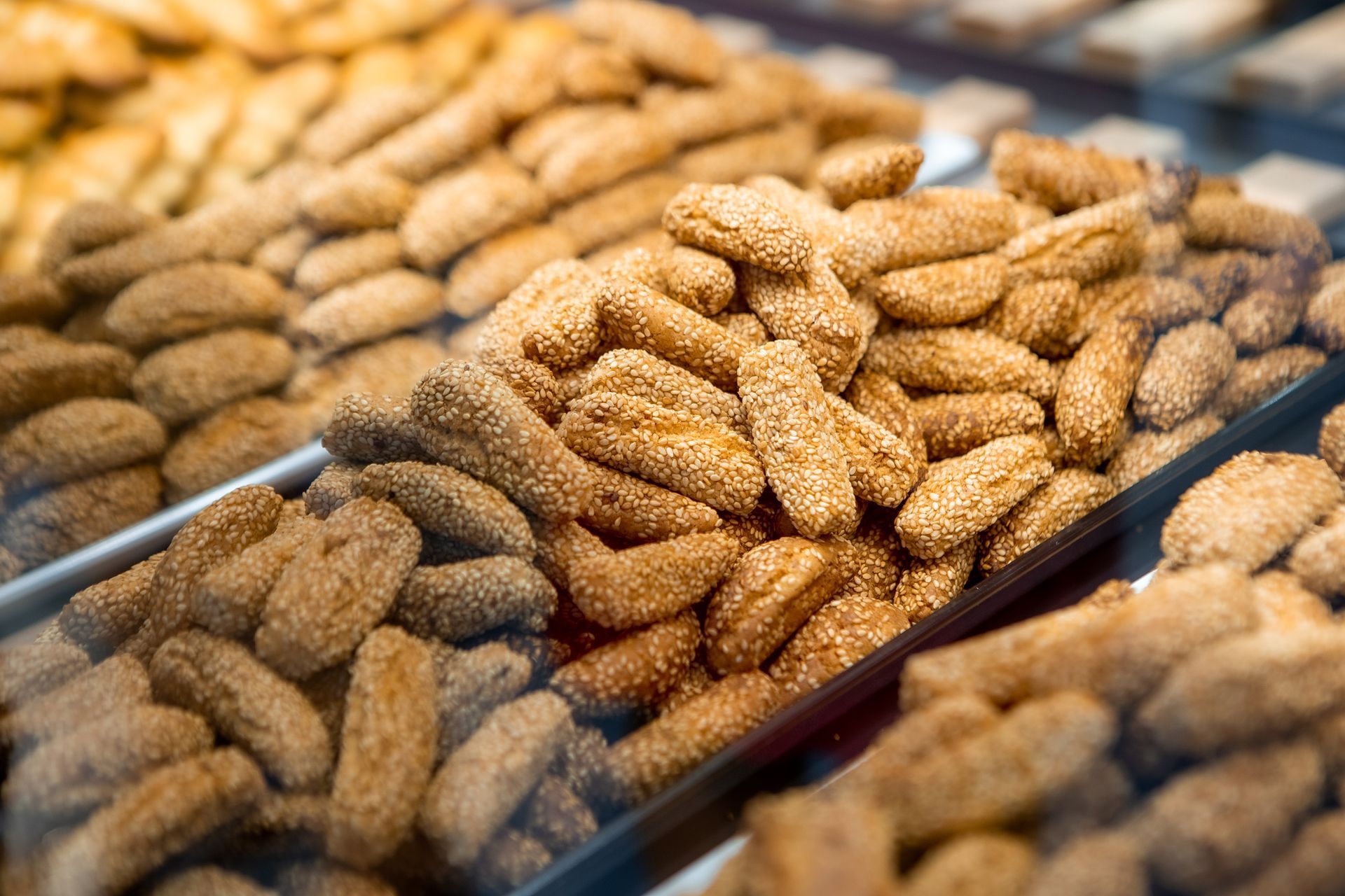 Biscotti ricoperti di sesamo cotti al forno e esposti in una vetrina.
