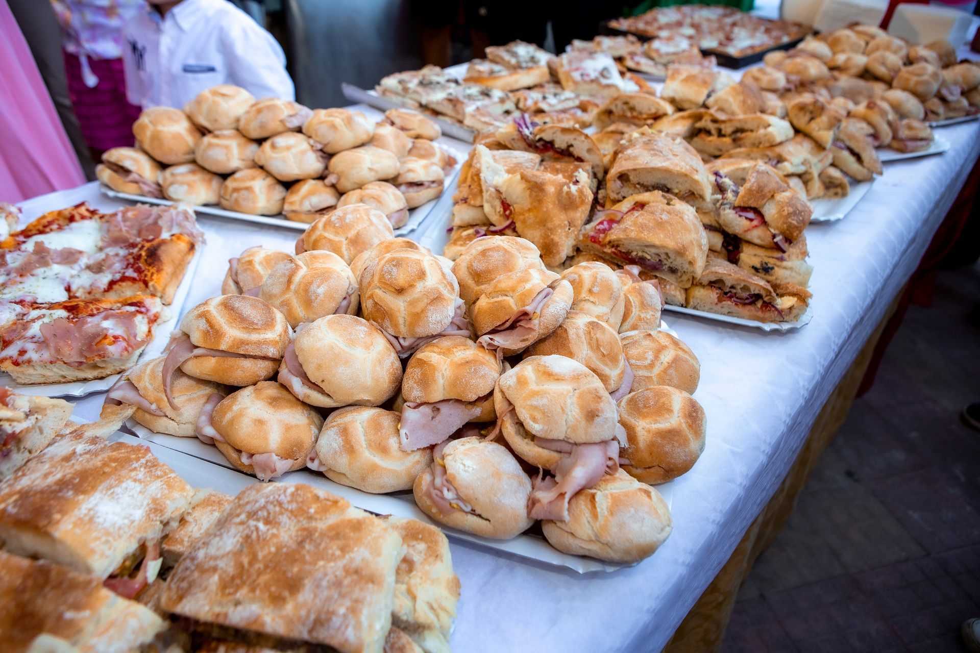 Tavolo buffet con vari panini, pizza e pasticcini.