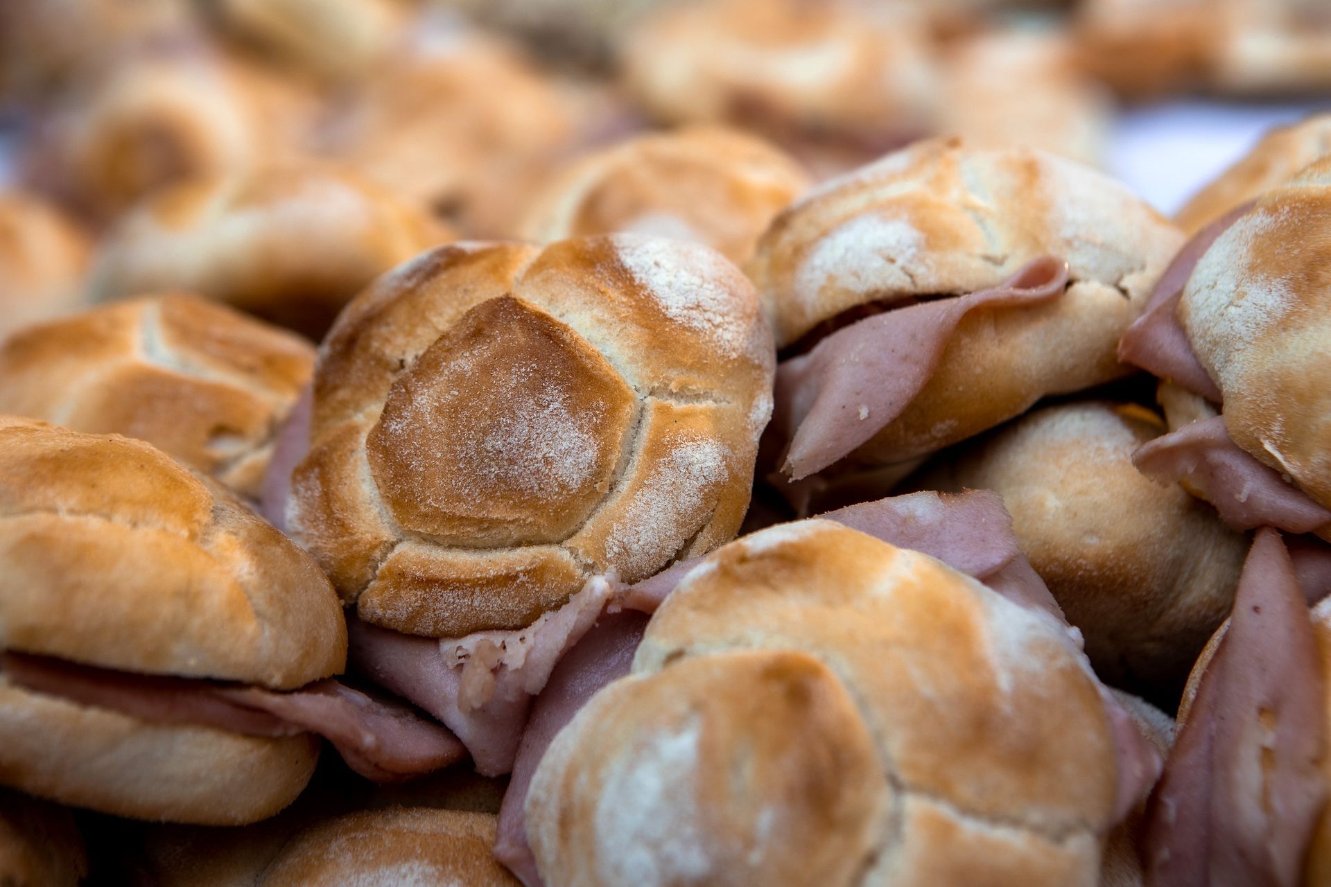 Primo piano di tanti piccoli panini rotondi, ripieni di carne. Il pane è dorato.