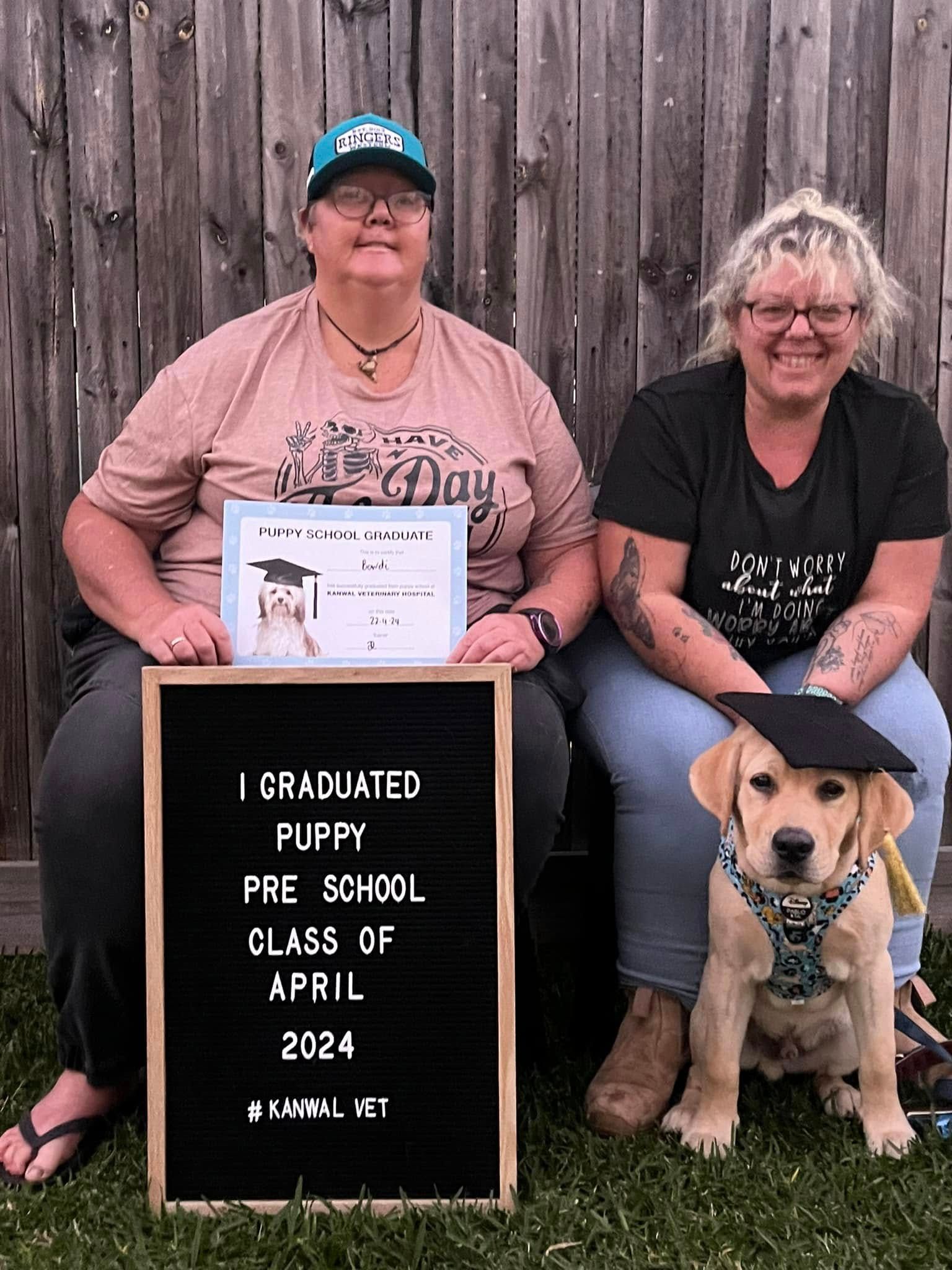 Two People and A Puppy Pose For Graduation Photo With Sign — Kanwal Veterinary Hospital In Kanwal, NSW