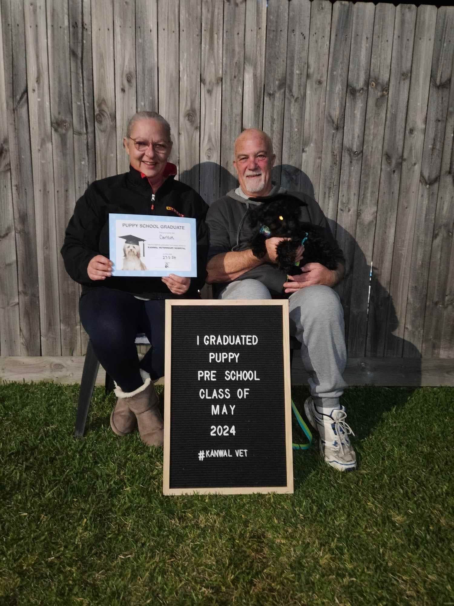 Couple With Puppy and Graduation Sign — Kanwal Veterinary Hospital In Kanwal, NSW