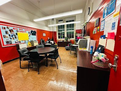 Office with red walls, round table with chairs, and various office supplies.