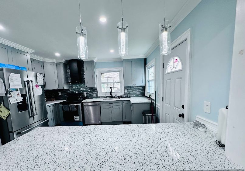 Modern kitchen with grey cabinets, blue walls, and pendant lights.