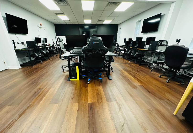 Gaming room with computers, chairs, and a black and blue gaming chair in the center.
