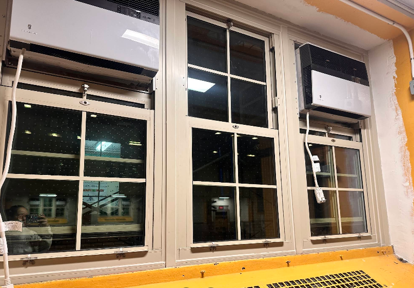 Three windows with air conditioners, in a room with yellow wall and trim.