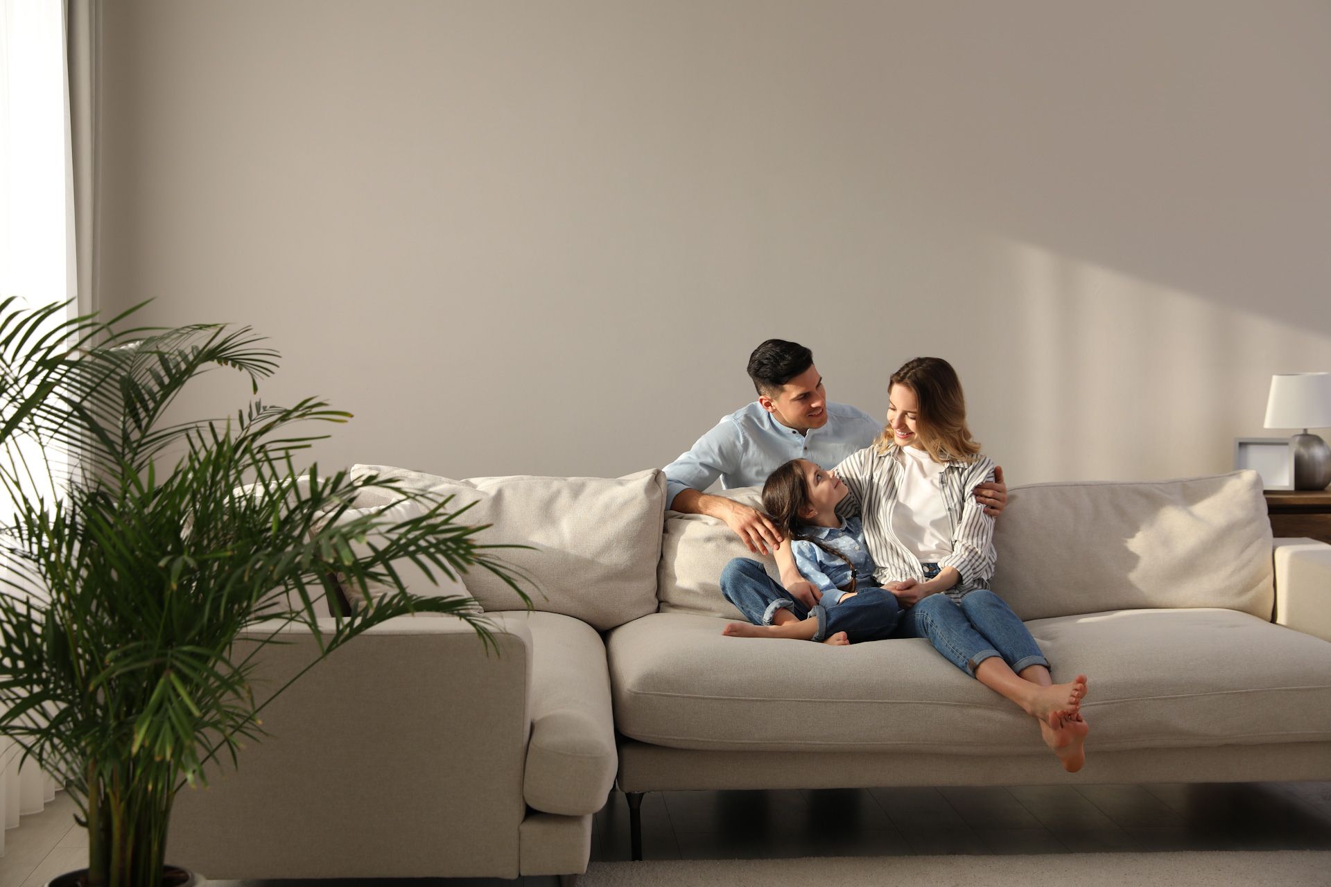 A family sits on a white couch in a living room