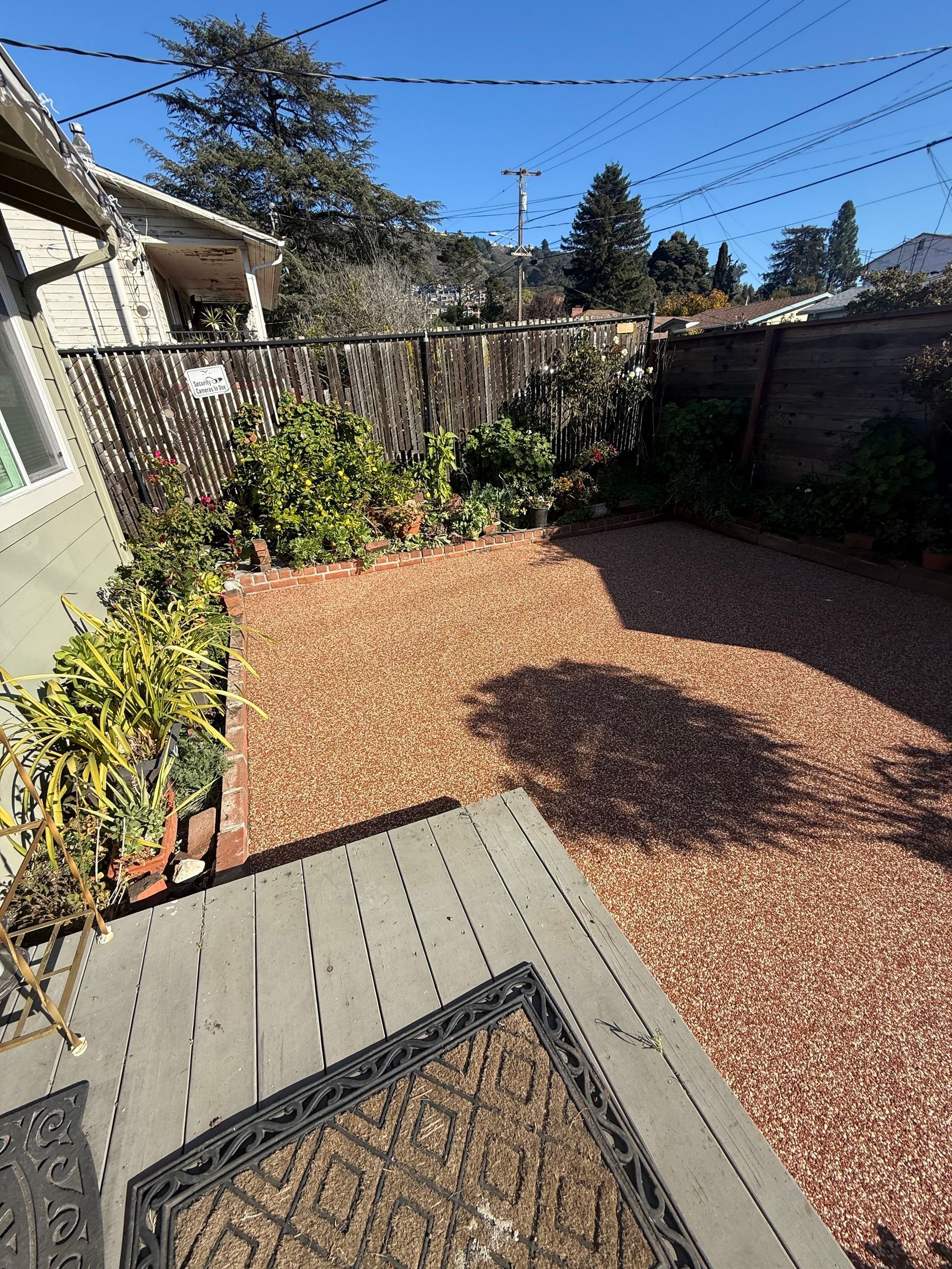 Small backyard with wood chip ground cover, wooden deck and fence. Sunny day.