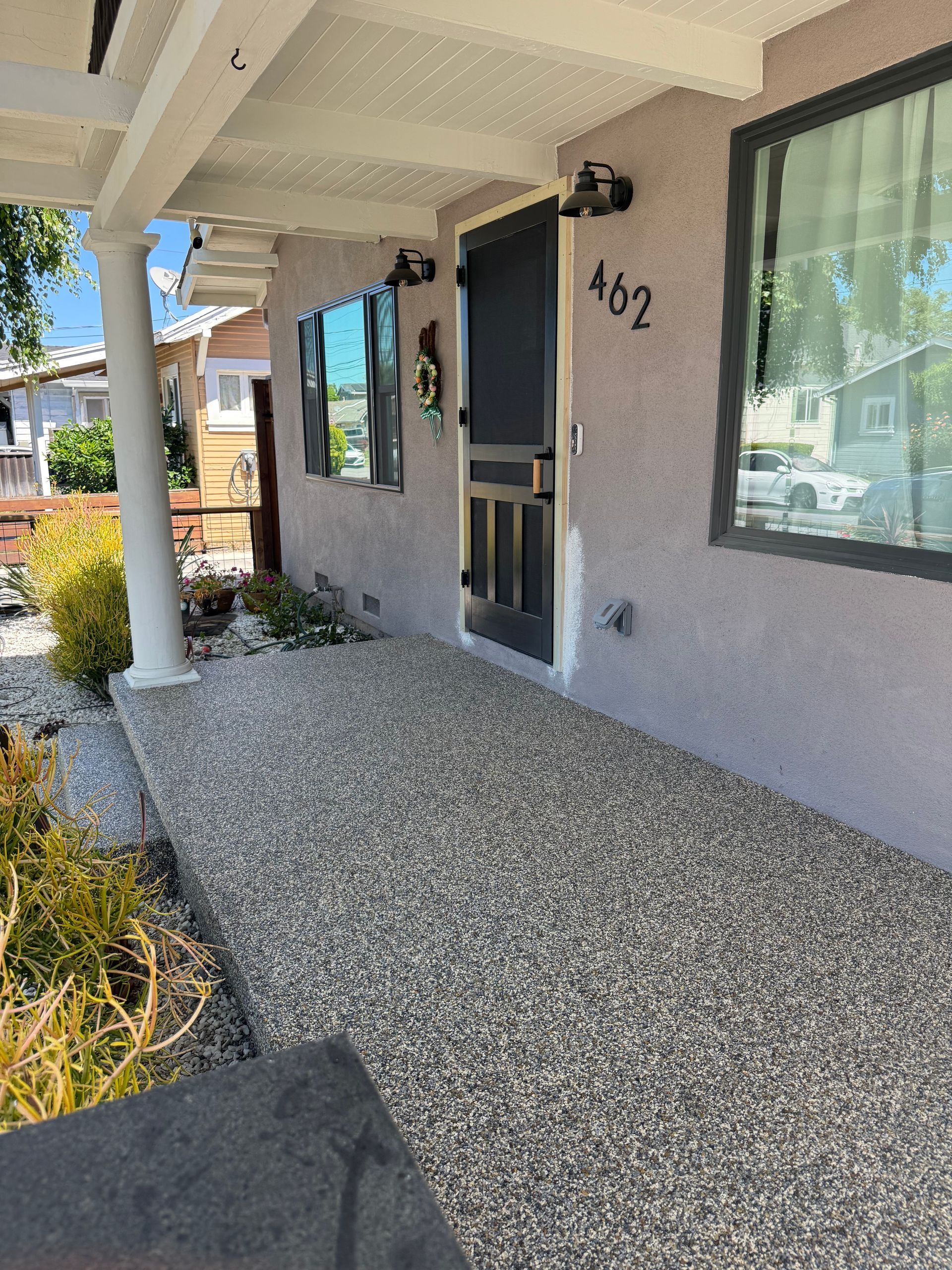 Front porch with white columns, gray stucco wall, black door, and house number 462.