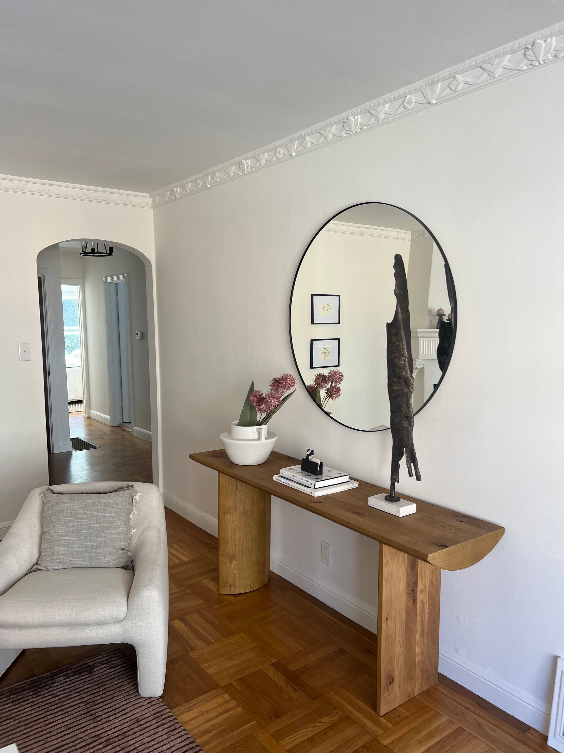 A living room with a wooden table , chair , and mirror.