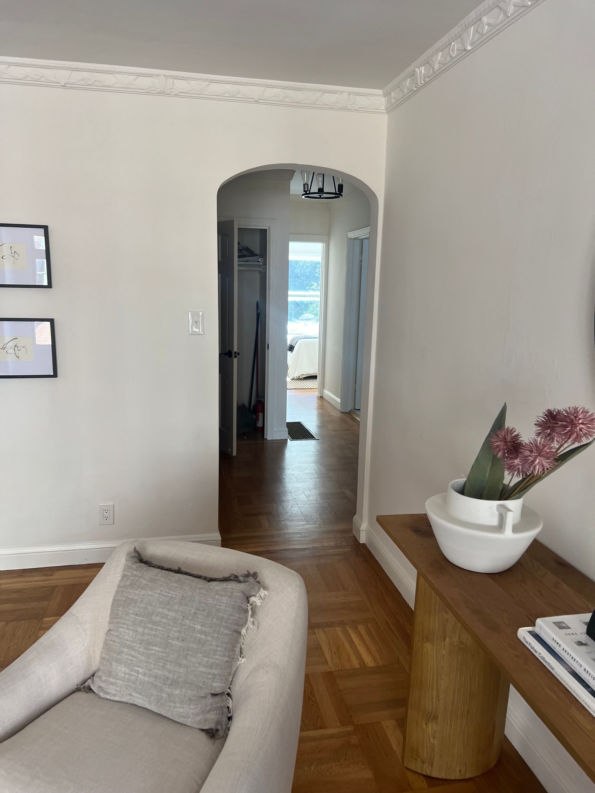 A living room with a chair a table and a vase of flowers