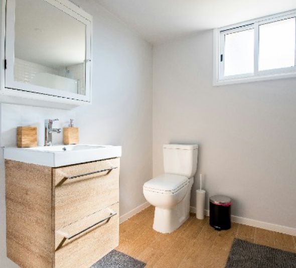 A bathroom with a toilet , sink and mirror.