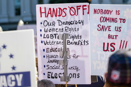 Protest signs listing rights: Democracy, women, LGBTQ, veterans, education, human, social security, elections; 