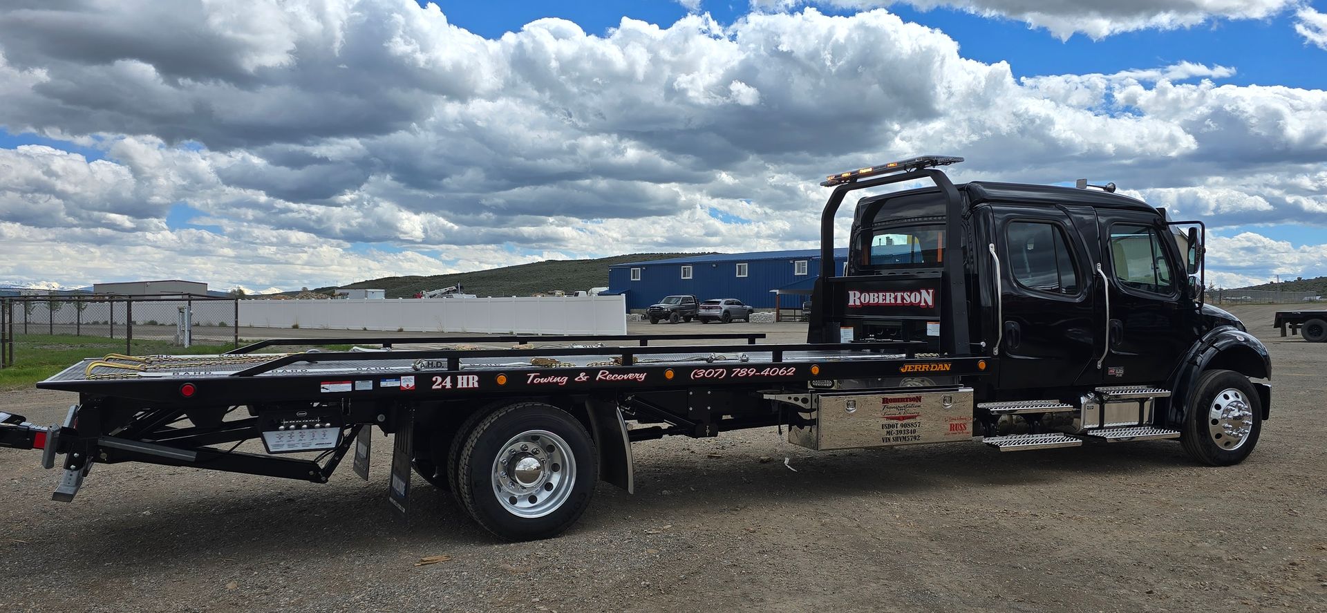Two tow trucks are parked in front of a blue building — Evanston, WY — Robertson Transportation Inc. Towing and Recovery
