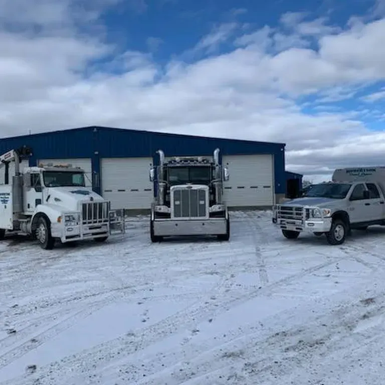 Three trucks are parked in front of a building in the snow — Evanston, WY — Robertson Transportation Inc. Towing and Recovery