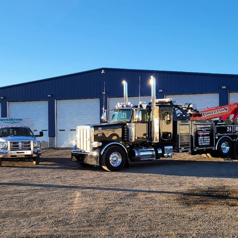 Two tow trucks are parked in front of a blue building — Evanston, WY — Robertson Transportation Inc. Towing and Recovery
