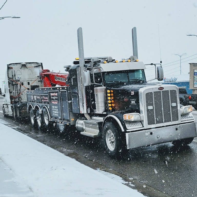 A tow truck is driving down a snowy street — Evanston, WY — Robertson Transportation Inc. Towing and Recovery