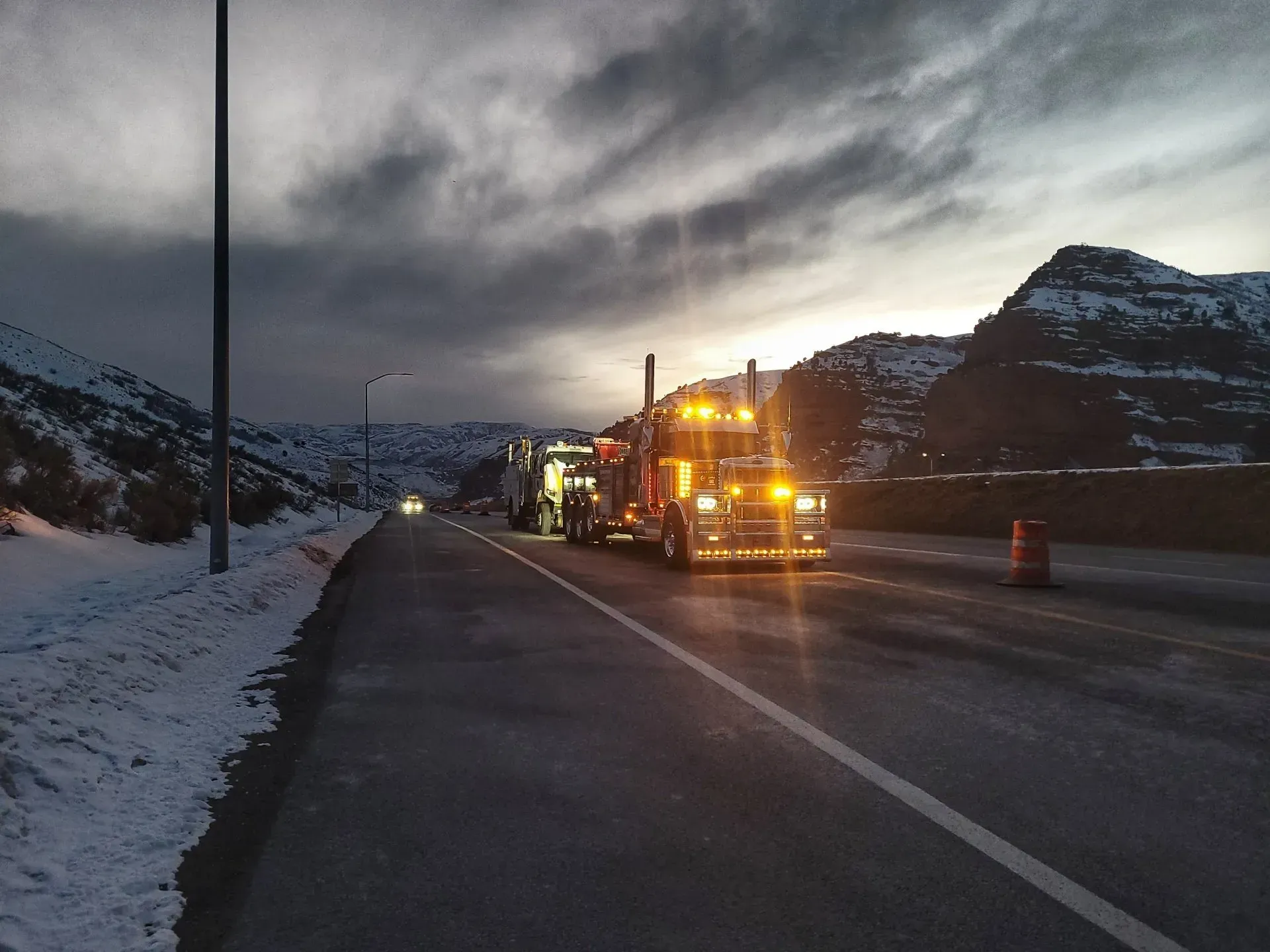 A truck is driving down a snowy highway at night — Evanston, WY — Robertson Transportation Inc. Towing and Recovery