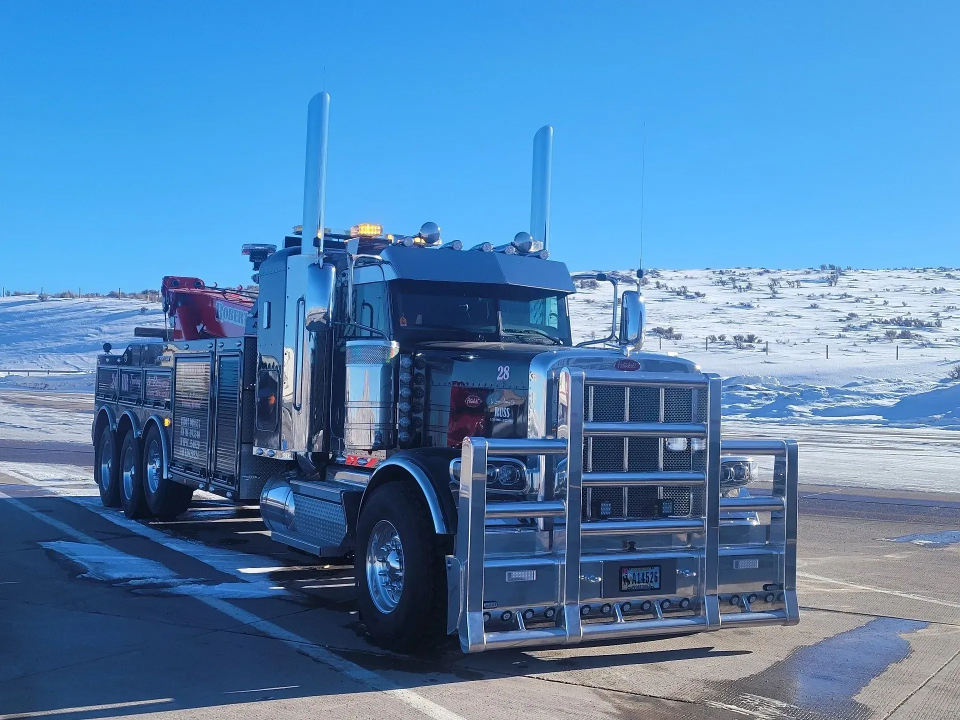 A tow truck is parked in a parking lot with snow in the background — Evanston, WY — Robertson Transportation Inc. Towing and Recovery