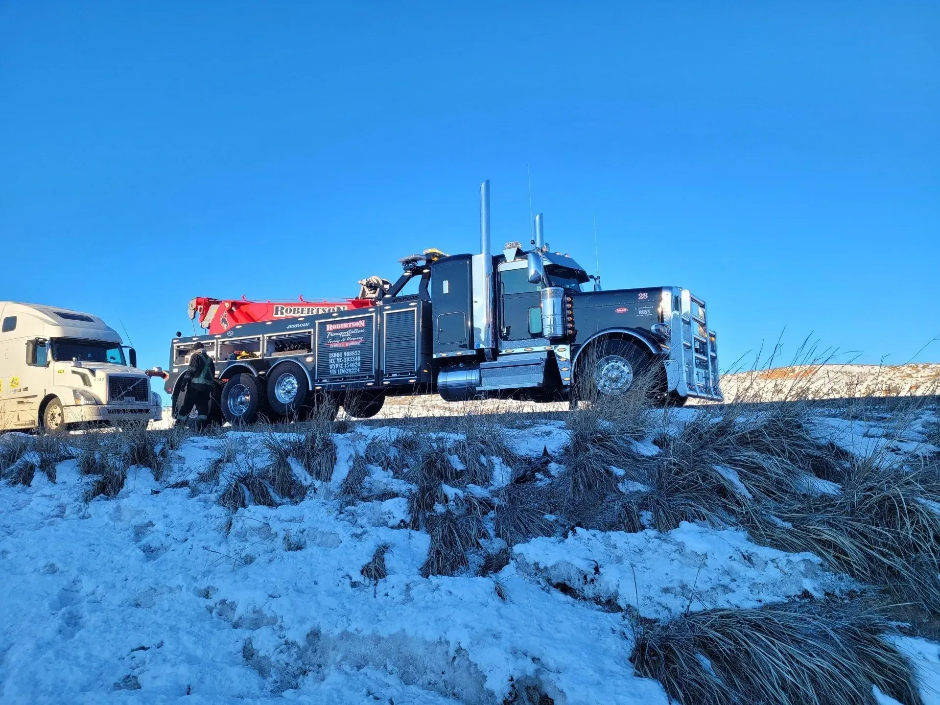 A tow truck is parked on the side of the road in the snow — Evanston, WY — Robertson Transportation Inc. Towing and Recovery