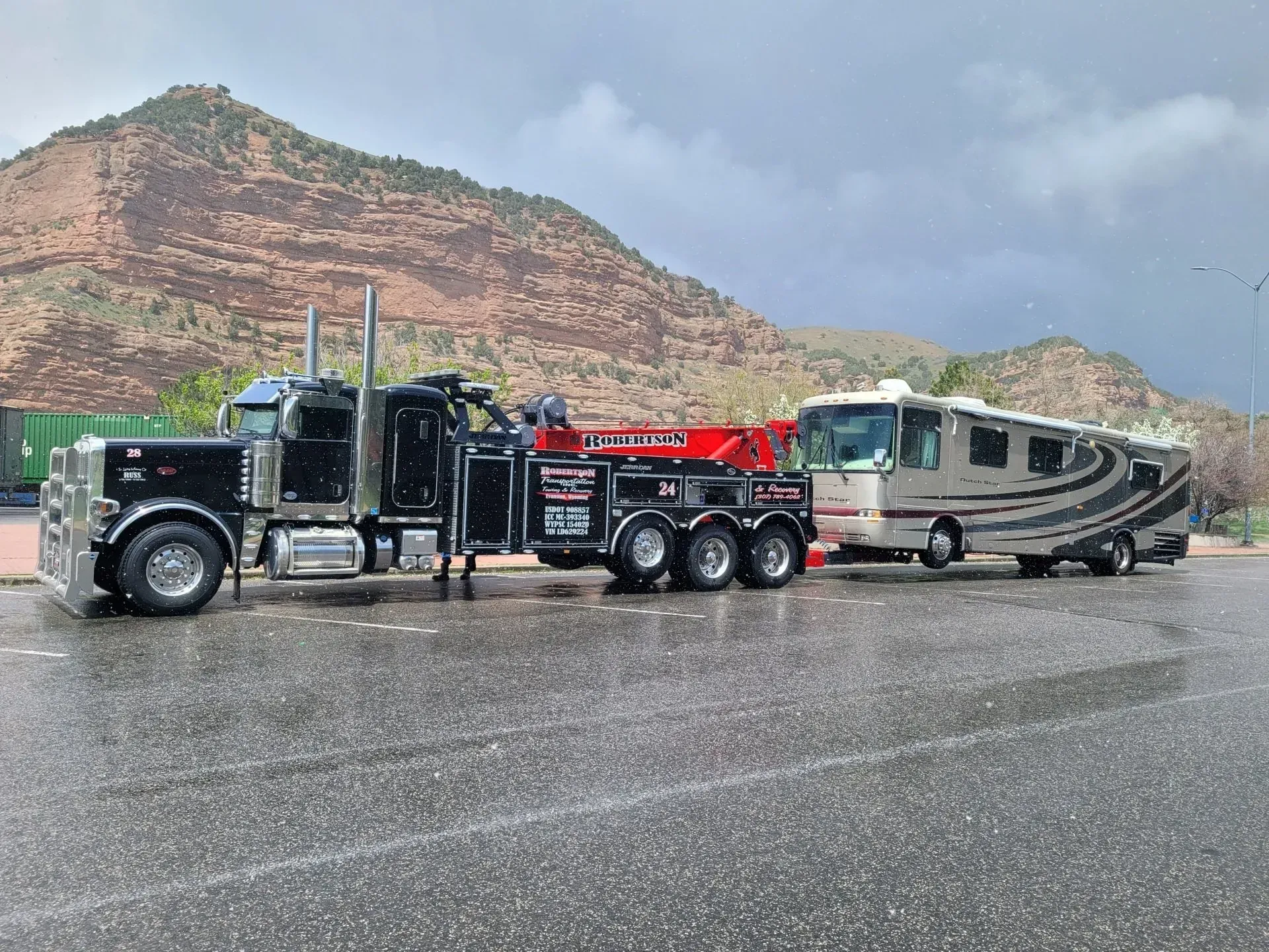 A tow truck is towing a rv in a parking lot — Evanston, WY — Robertson Transportation Inc. Towing and Recovery