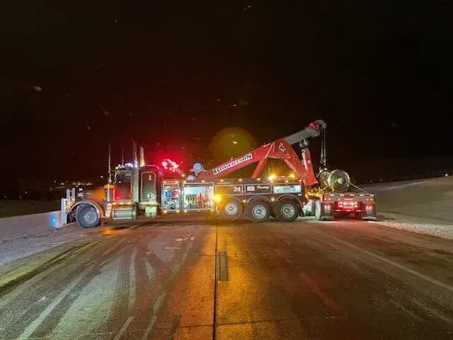 A tow truck is parked on the side of the road at night — Evanston, WY — Robertson Transportation Inc. Towing and Recovery