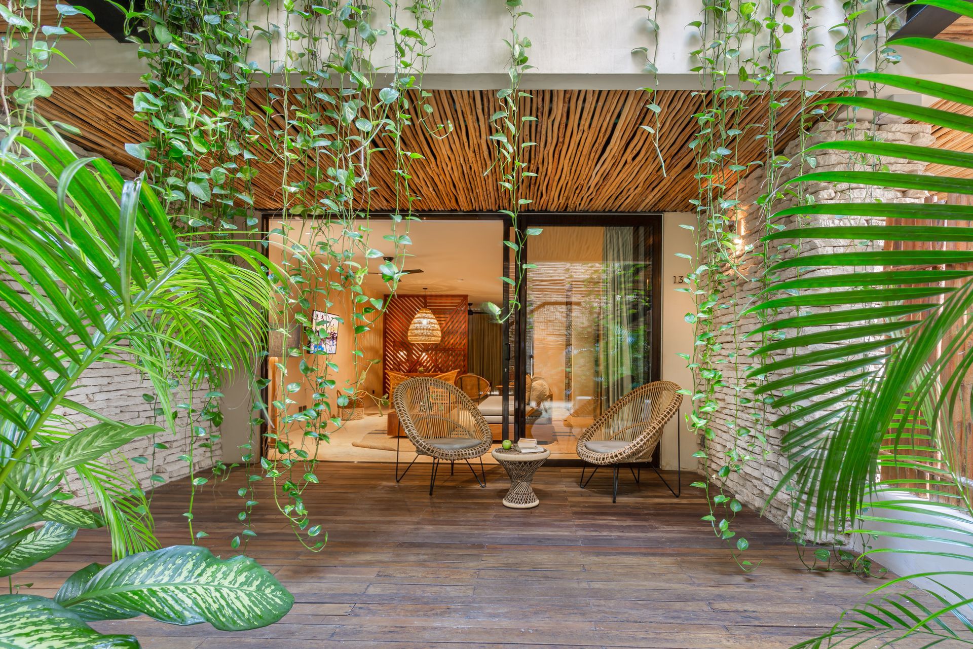 A patio with chairs , a table and plants hanging from the ceiling.