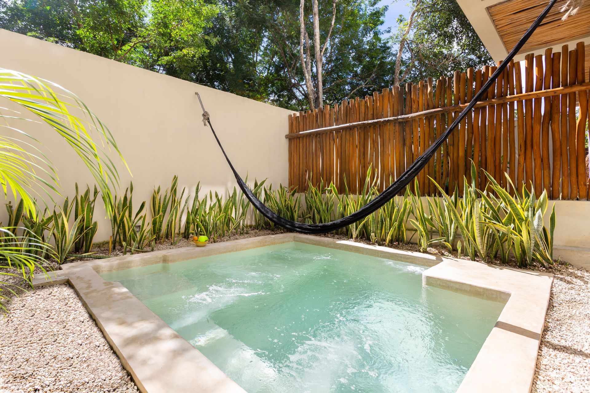 A small swimming pool with a hammock hanging over it.
