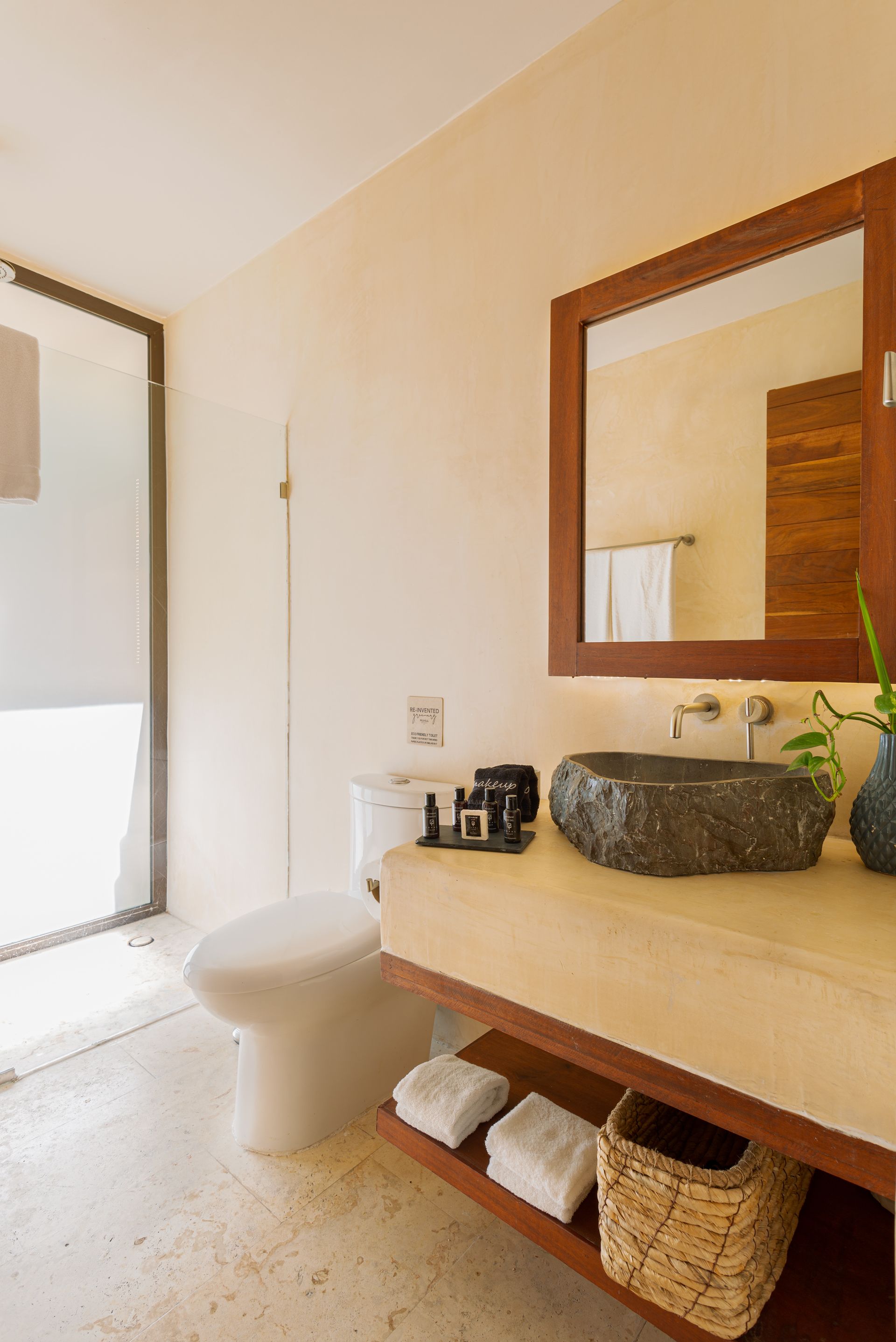 A bathroom with a toilet , sink and mirror.