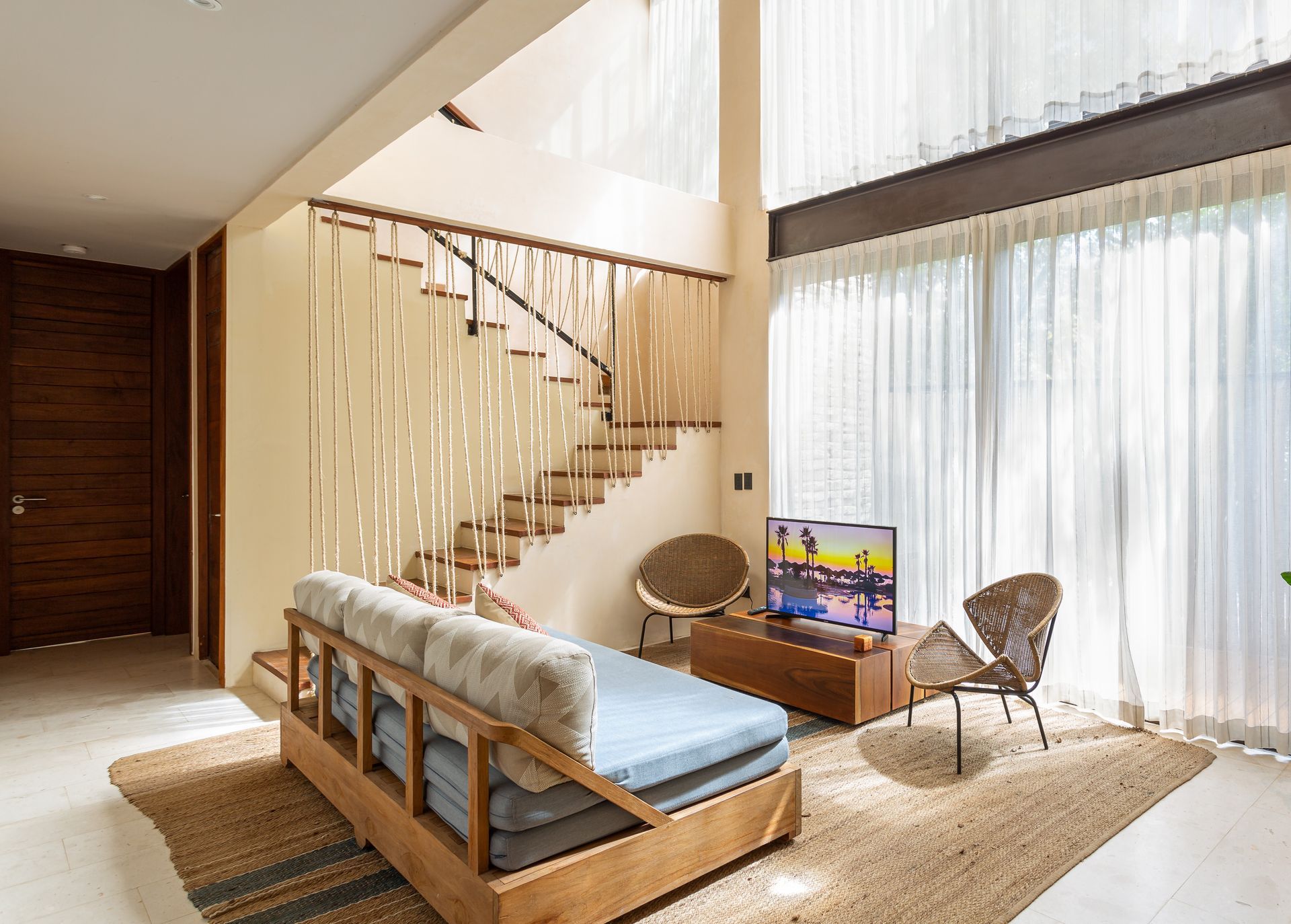A living room with a couch , chairs , television and stairs.