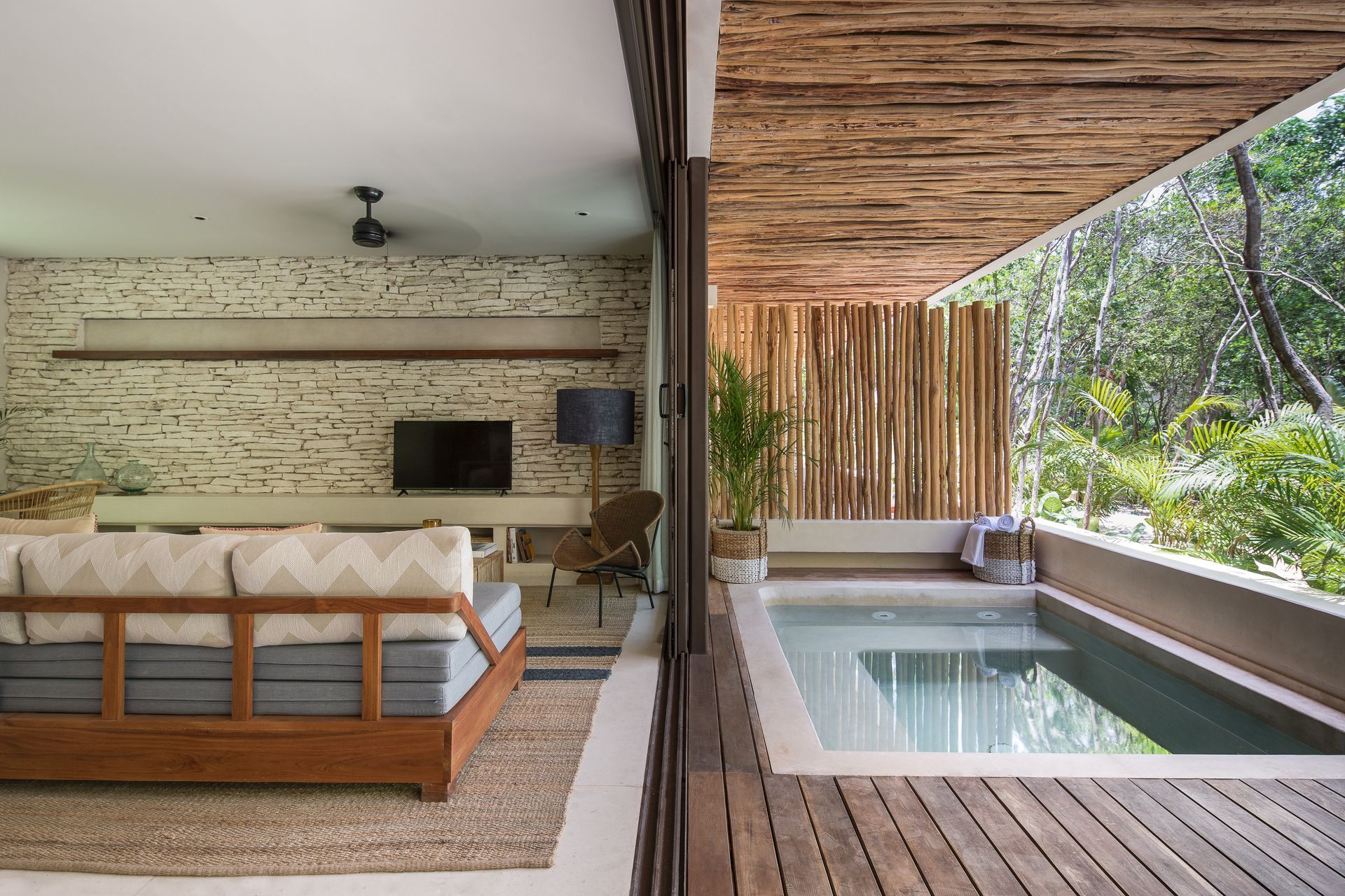 A living room with a couch and a television next to a swimming pool.