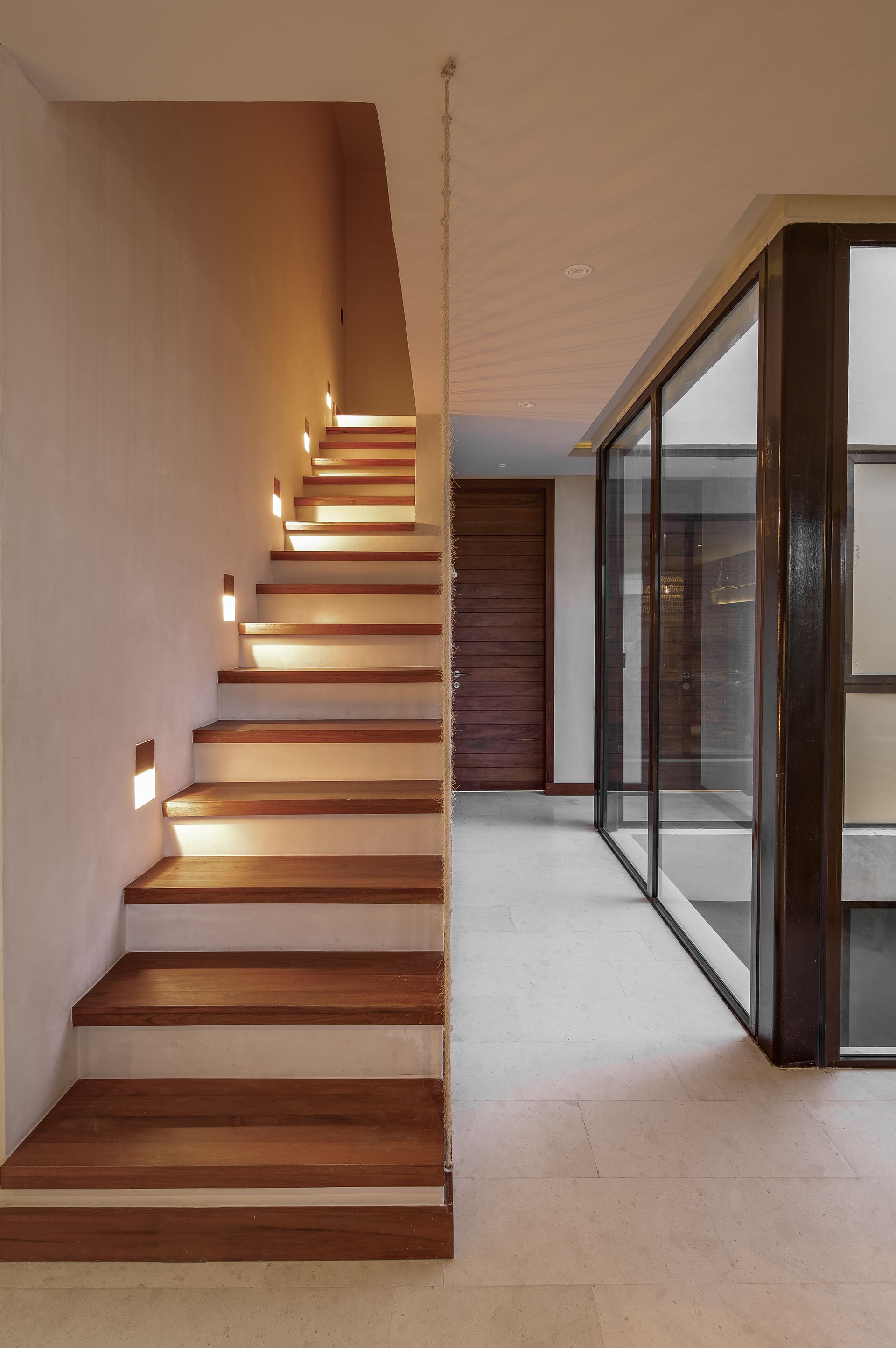 A wooden staircase with lights on the steps in a hallway