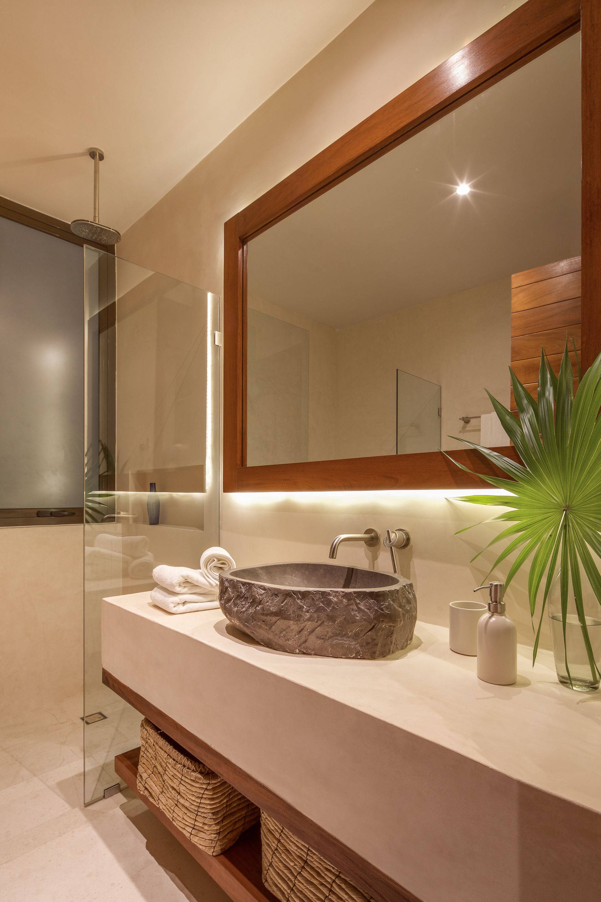 A bathroom with a sink , mirror and walk in shower.
