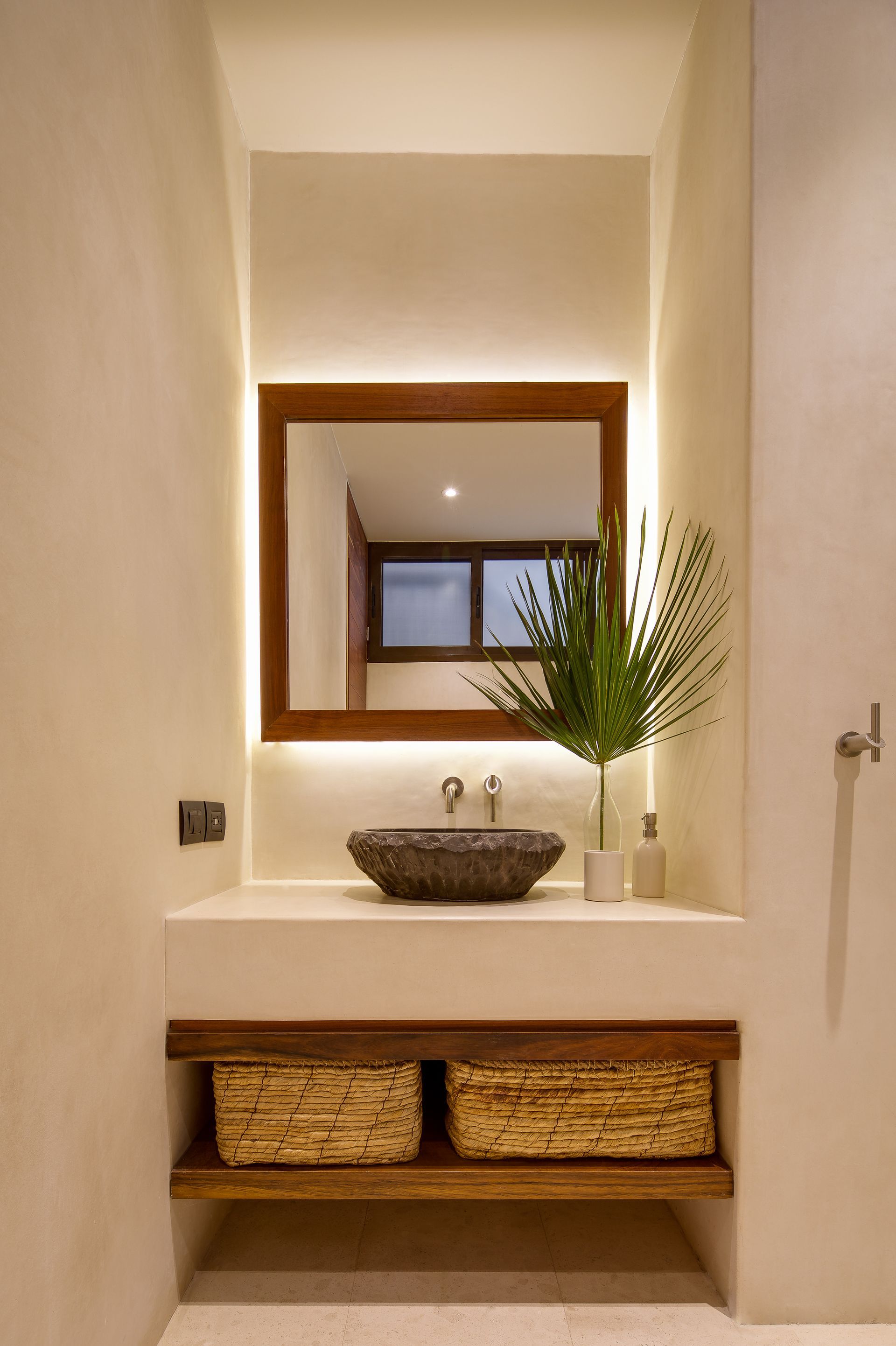 A bathroom with a sink , mirror and wicker baskets.